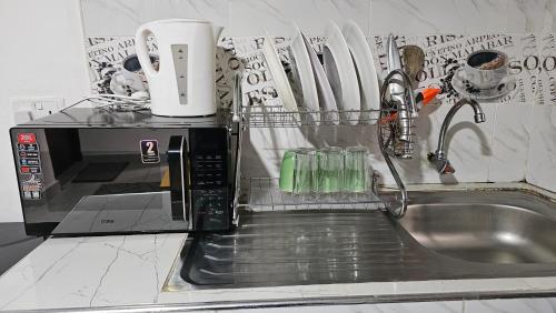a kitchen sink with a microwave on top of it at Executive Studio in Juja
