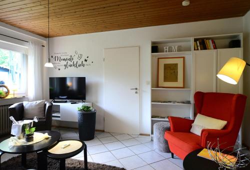 a living room with a red couch and a tv at Haus Sonnenschein in Wiltingen