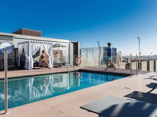 a man and woman standing on top of a building with a pool at Novotel Madrid Center in Madrid