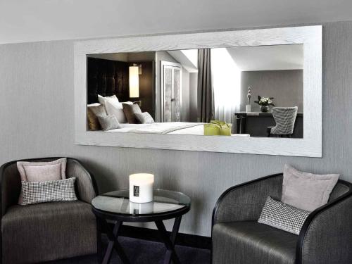 a hotel room with a bed and a table and chairs at La Cour des Consuls Hotel & Spa Toulouse - MGallery Collection in Toulouse