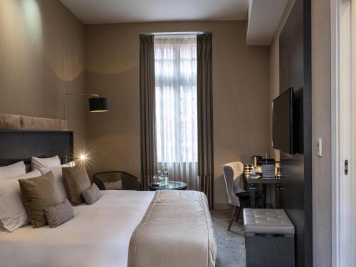 a hotel room with a large bed and a window at La Cour des Consuls Hotel & Spa Toulouse - MGallery Collection in Toulouse