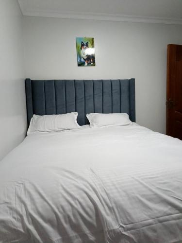 a large white bed with a blue headboard in a bedroom at Qara Homes One Bedroom, Juja in Juja
