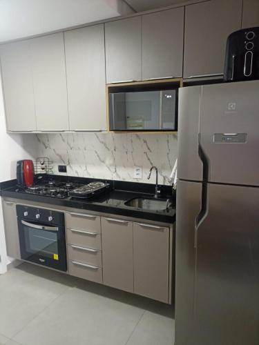 a kitchen with a stainless steel refrigerator and a sink at Edifício Concept in Marília