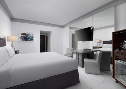 a white hotel room with a bed and a desk at Nautilus Sonesta Miami Beach in Miami Beach