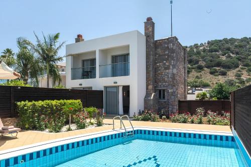 a villa with a swimming pool in front of a house at The Noverian Scenic Crete 5 Star Hilltop Villa Resort & Spa in Malia