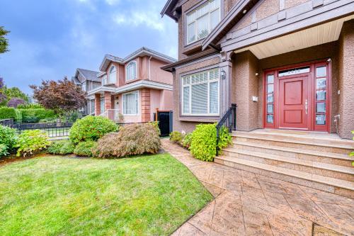 a house with a red door and a yard at Cozy two beds lower level suite in Vancouver West in Vancouver
