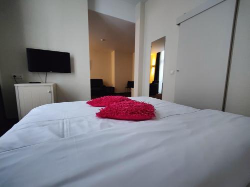 a pink flower laying on top of a white bed at Hotel Florent in Lier