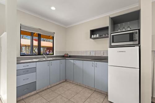 a kitchen with a white refrigerator and a microwave at ASURE Oak Estate Motor Lodge in Greytown