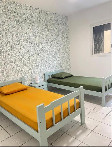 a room with two beds and a wall at La Terrasse des Maldives in Saint-Paul
