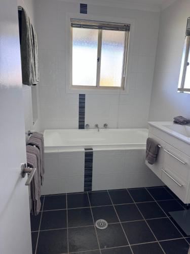 a white bathroom with a tub and a window at Entire home near South West Rocks Beautiful Views in Pelican Island