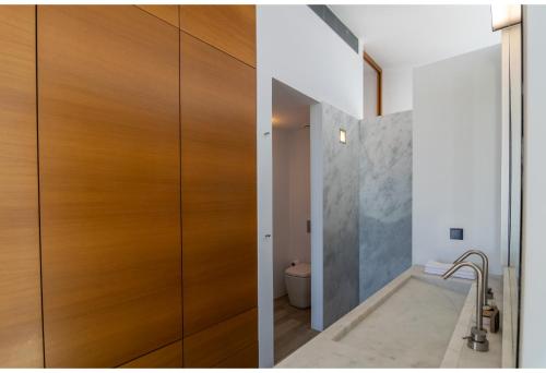 a bathroom with a wooden door next to a toilet at Hourglass Villa's Milos in Psathadika
