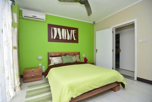 Dormitorio verde con cama y pared verde en Turquoise Bay Beach Apartments Trou d'Eau Douce, en Trou d'Eau Douce