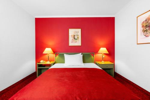 a red room with a bed and two lamps at Hotel-Restaurant Schwanen in Weil am Rhein