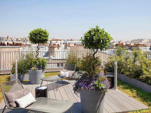 a balcony with chairs and tables and potted plants at Boutet Bastille Hotel Paris - MGallery Collection in Paris