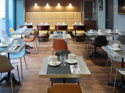 a dining room with tables and chairs with cups on them at Boutet Bastille Hotel Paris - MGallery Collection in Paris