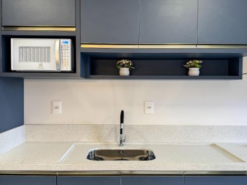 a kitchen with a sink and a microwave at Lindo apto com piscina em Bombas / SC in Bombas