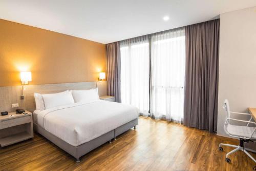 a hotel room with a bed and a desk and a window at Sonesta Hotel Ibagué in Ibagué