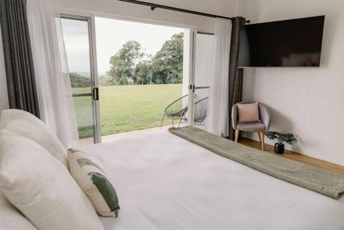 a bedroom with a bed and a large window at Elysian Hills in Carool