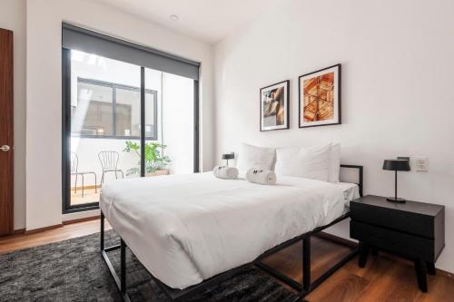 a white bedroom with a large bed and a window at Allan Poe 343 by Wynwood House in Mexico City