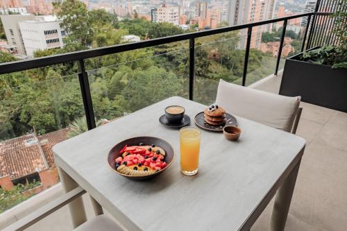 a table with a bowl of fruit and a glass of orange juice at Kiin Living- "Child-free coliving" in Medellín