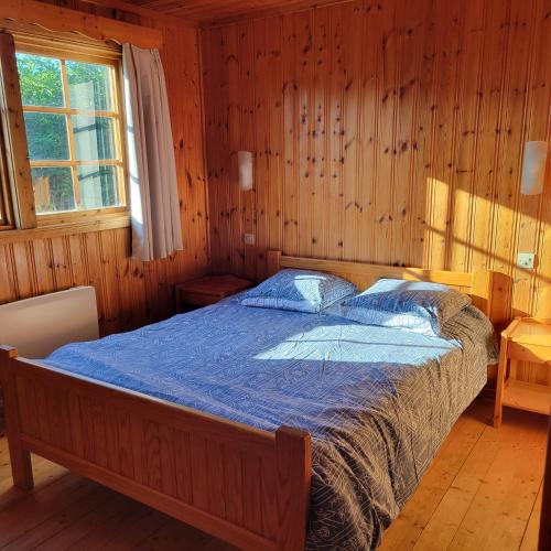 una camera da letto con un letto in una stanza di legno di Les Petites Cabanes de Machiel a Machiel