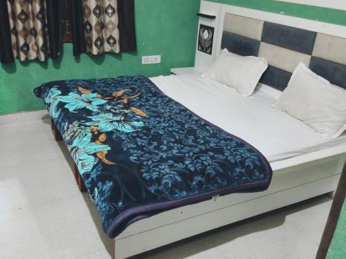 a bed with a blue and white blanket on it at Gopi Dham in Chhatikara