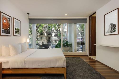 a bedroom with a large bed and a large window at Allan Poe 343 by Wynwood House in Mexico City