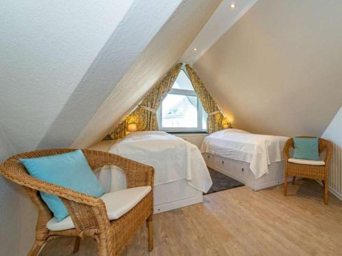 een slaapkamer op zolder met 2 bedden en rieten stoelen bij One-bedroom apartment in Wenningstedt