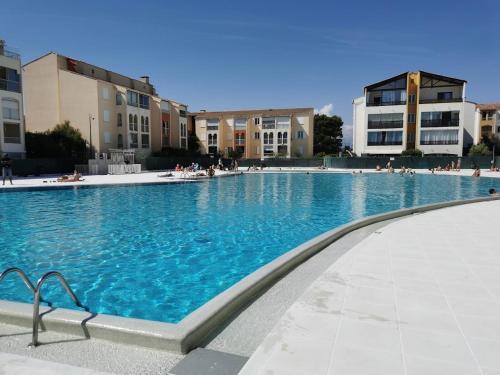 ein großer Pool mit blauem Wasser vor den Gebäuden in der Unterkunft LAGON BLEU - Proche Gare Routière - Terrasse & Piscine - 3Km PLAGE - PARKING & WIFI Gratuit - OFFRE SPECIALE in Fréjus