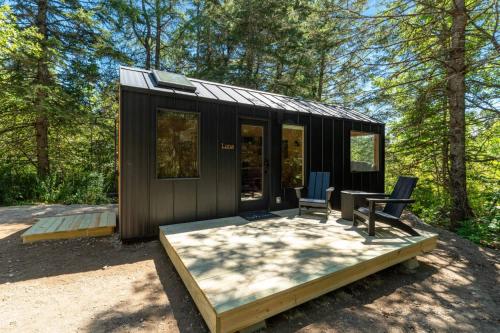 a black tiny house with two chairs and a table at Luna Nook-Cabin with tub Queen Bed & pullout sofa in Sullivan