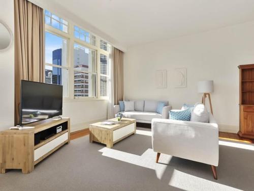 a living room with a couch and a tv at Beautiful and Spacious 1BR in CBD by Zodiak Stays in Auckland