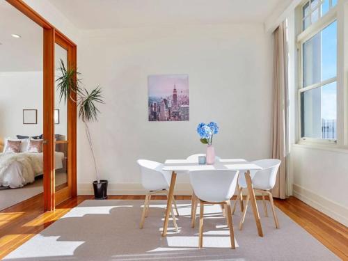 a white dining room with a table and chairs at Beautiful and Spacious 1BR in CBD by Zodiak Stays in Auckland