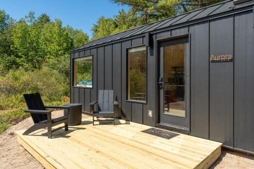 a black tiny house with a wooden deck at Aurora Nook-Cabin with Shower & Queen Bed in Sullivan