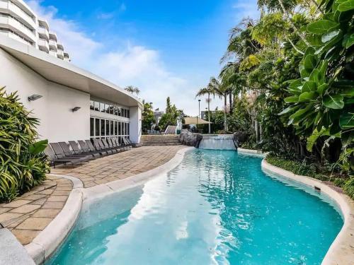 a swimming pool in front of a house with blue water at Lovely Apartment - Gym & Parking by Zodiak Stays in Auckland