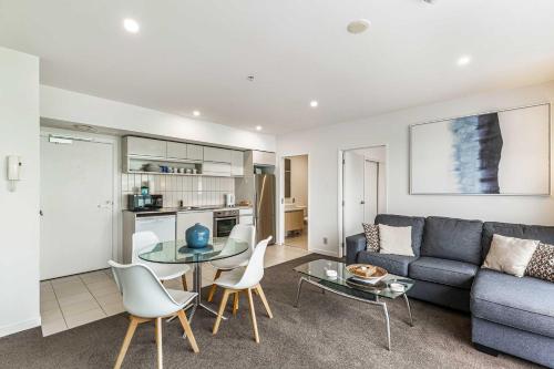 a living room with a couch and a table and chairs at Beautiful 2BR - Pool, Gym & Parking Zodiak Stays in Auckland