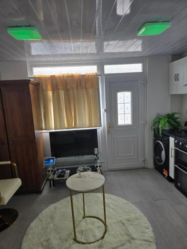 a living room with a table and a television at Guest house in Le2 in Leicester