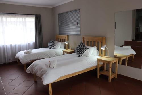 a bedroom with two beds and two lamps and a window at Sleep-A-Lot in Piet Retief