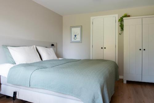 a white bedroom with a bed and white cabinets at Het Moleneind - Studio en Vakantiehuis in Kapel-Avezaath