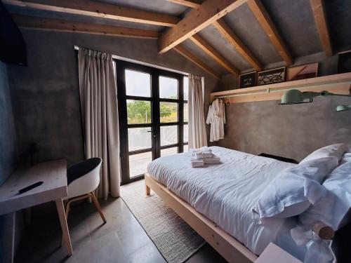 a bedroom with a bed and a desk and a window at Casa da Eira, Casaspensadas in Juncal