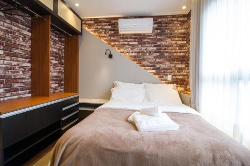 una camera da letto con un letto grande con un muro di mattoni di Studio Silva Jardim - Próx Shop Estação com VAGA a Curitiba