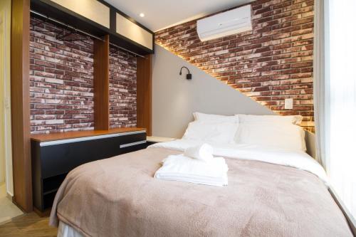 una camera da letto con un letto grande con un muro di mattoni di Studio Silva Jardim - Próx Shop Estação com VAGA a Curitiba