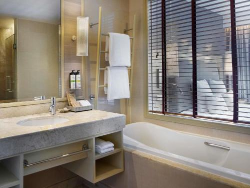 a bathroom with a sink and a bath tub at Pullman Phuket Panwa Beach Resort in Panwa Beach
