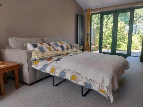 HindheadにあるSelf-contained 2-story accommodation in Grayshottのベッドとソファと窓のある寝室