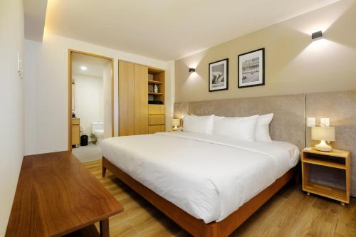 a bedroom with a large white bed and wooden floors at Colima 340 by Wynwood House in Mexico City