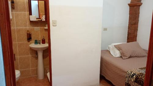 a small bathroom with a bed and a sink at Hotel y Jardines Casa Búho in Antigua Guatemala