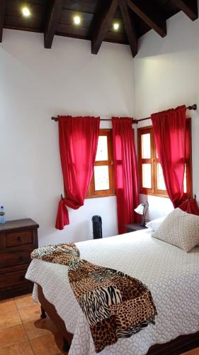 a bedroom with a large bed with red curtains at Hotel y Jardines Casa Búho in Antigua Guatemala