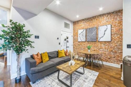 a living room with a couch and a brick wall at Lovely 2BR w Patio - 10 mins to DT - Sleeps 10 in Philadelphia