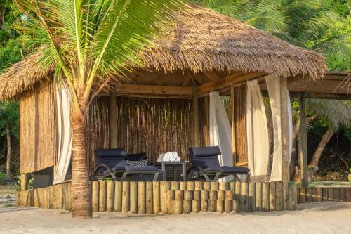 a hut with two chairs and a table and a palm tree at Scrub Island Resort, Spa & Marina in The Mill