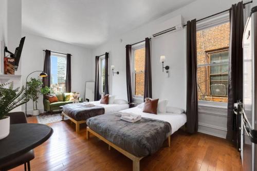 a room with two beds and a couch and windows at New Studio in Center City that Sleeps 4 with Fast Wifi in Philadelphia