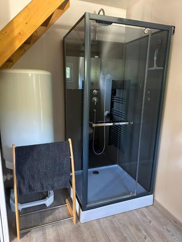 a shower with a glass door next to a chair at Le LODGE De La Sainte Baume in Plan dʼAups